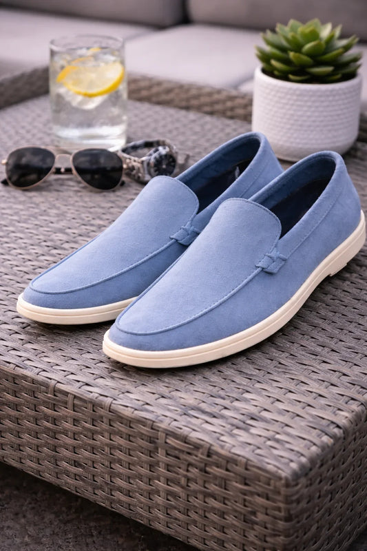 Paire de mocassins bleu clair pour homme sur table en rotin, ambiance estivale.