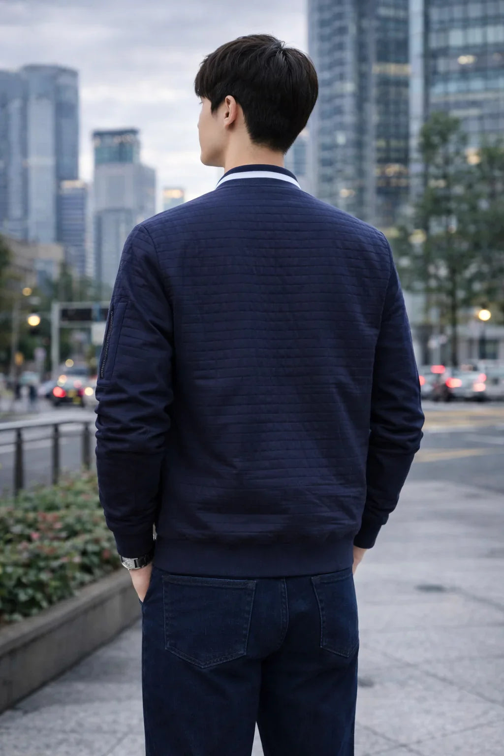 Homme de dos en veste matelassée bleu marine et jean, environnement urbain moderne